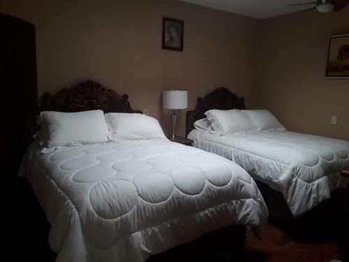 a bedroom with two beds with white comforters at Posada Las Reynas in Mineral de Pozos