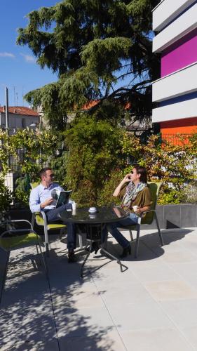 two people sitting at a table with their laptops at Privilège Hôtel & Apparts Eurociel Centre Comédie in Montpellier