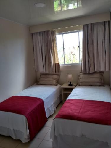 two beds in a room with a window at Hotel Maea Hare Repa in Hanga Roa