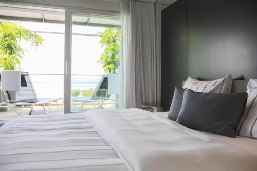 a bedroom with a large white bed with a large window at Marina Lachen in Lachen