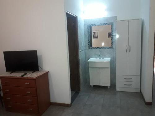 a bathroom with a sink and a tv on a dresser at Departamentos del centro in Villa Mercedes