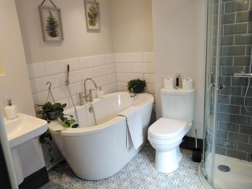 a bathroom with a tub and a toilet and a sink at Aubrey Cottage in Cowbridge