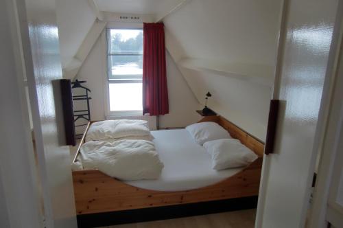 1 dormitorio con 1 cama con sábanas blancas y ventana en Huisje 59, en Nieuwe-Niedorp