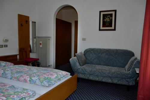 a bedroom with a bed and a couch and a chair at Pension Pichler in Chienes
