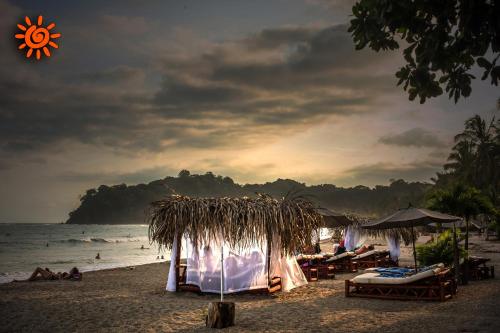 a beach with tables and umbrellas and the ocean at Locanda Samara Beach in Sámara