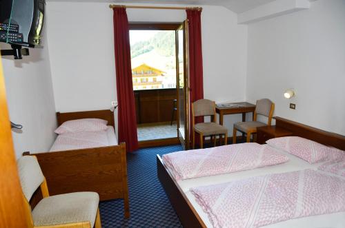 a bedroom with two beds and a table and chairs at Pension Pichler in Chienes