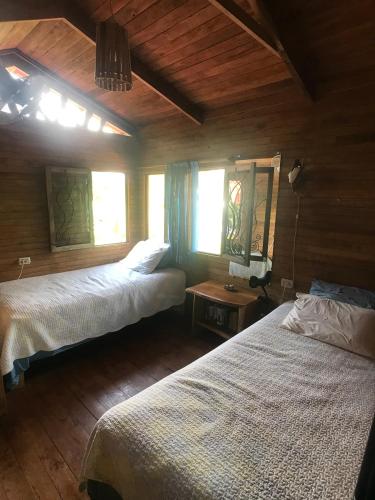 a bedroom with two beds and two windows at Casita de los Sueños in Cabuya