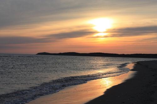 a sunset on the beach with the sun setting at Codroy Valley Cottage Country in Doyles