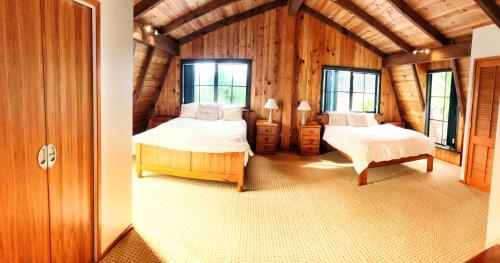 a bedroom with two beds in a log cabin at Coastal Chalet Suites Whangaroa in Kaeo