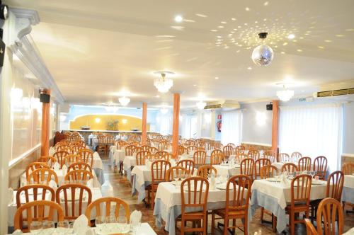 un comedor con mesas blancas y sillas de madera en Hostal Can Marinés, en Sant Carles de la Ràpita