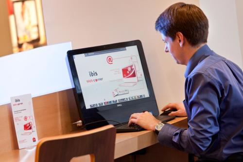 a man standing in front of a laptop computer at ibis Beauvais Aéroport in Beauvais