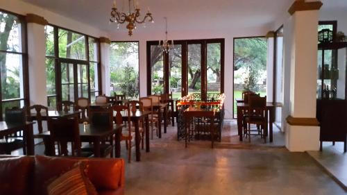 a dining room with tables and chairs and windows at Estancia del Olivo in Chilecito