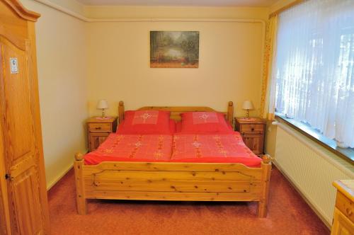 a bedroom with a wooden bed with red sheets and a window at Appartement Am Schulwald in Büsum
