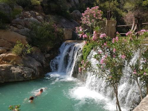 two people swimming in a waterfall in a pool at Residential jardín del pintor - la casa amarilla in Jacarilla