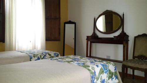 a bedroom with two beds and a mirror and a chair at Estancia del Olivo in Chilecito