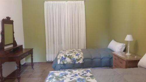 a bedroom with two beds and a dresser and a mirror at Estancia del Olivo in Chilecito