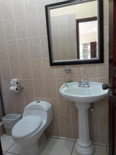 a bathroom with a toilet and a sink and a mirror at Hotel Carnaval in La Ceiba