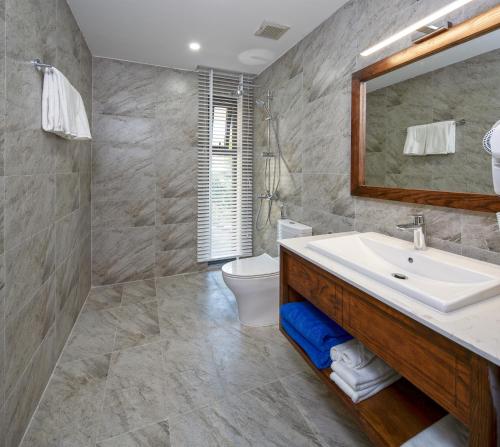 Un baño con lavabo, inodoro y espejo. en DANA RESIDENCE, en Da Nang