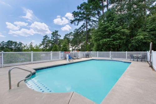 a large swimming pool with a fence and trees at Microtel Inn & Suites by Wyndham Augusta/Riverwatch in Augusta