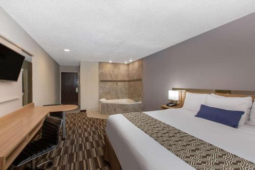 a hotel room with a large bed and a tub at Microtel Inn & Suites by Wyndham Augusta/Riverwatch in Augusta