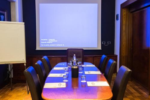 a conference room with a long table with chairs and a screen at Jet Hotel, Sure Hotel Collection by Best Western in Gallarate