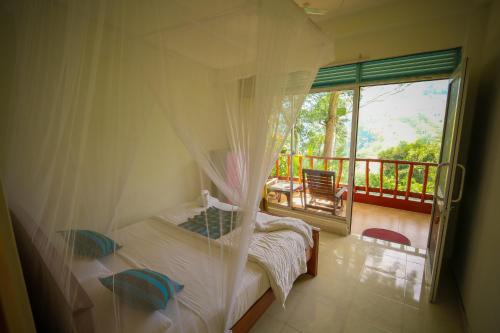 a bedroom with a bed and a balcony with a window at Ella waterfall view in Ella