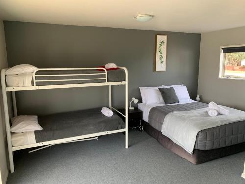 sypialnia z 2 łóżkami piętrowymi i łóżkiem w obiekcie Ranfurly Holiday Park & Motels w mieście Ranfurly