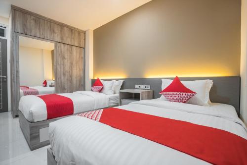 ein Hotelzimmer mit 2 Betten mit roter und weißer Bettwäsche in der Unterkunft OYO 1487 Residence Khoe in Jakarta