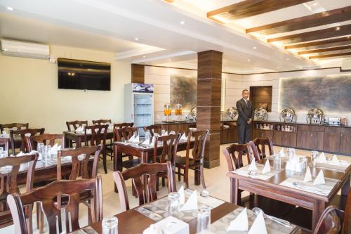 a man standing in a restaurant with tables and chairs at Ganapati Airport Hotel in Kathmandu