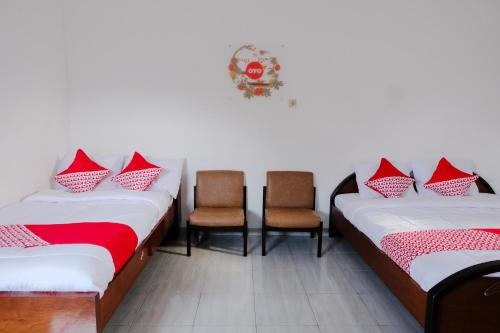 Cette chambre comprend 2 lits avec des oreillers rouges et blancs. dans l'établissement Super OYO Capital O 1176 J3 Residence Syariah, à Jember