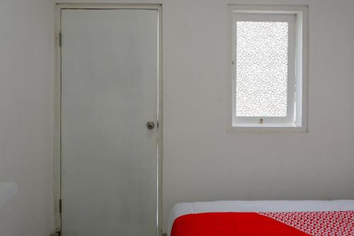 a bedroom with white walls and a window and a red bed at Capital O 1176 J3 Residence Syariah in Jember