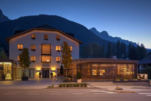 a large building in front of a mountain at night at Zur Post Residence Sexten in Sesto