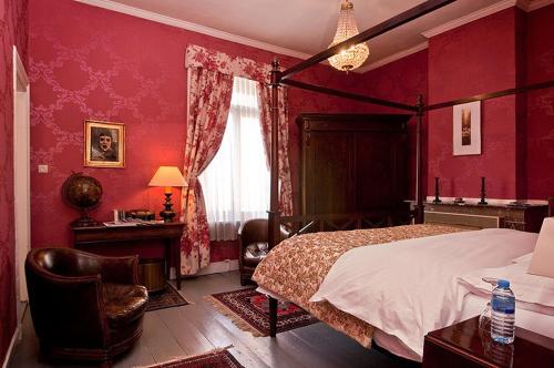 a bedroom with red walls and a bed and a chair at B&B The Baron in Antwerp
