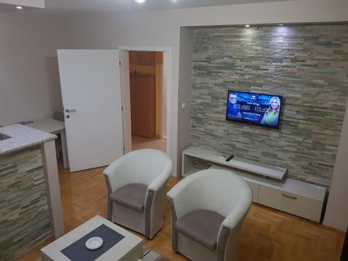 a living room with two chairs and a tv on a brick wall at Sunce in Šabac
