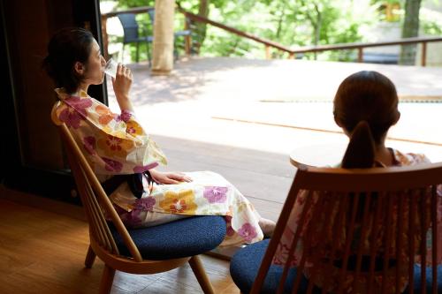 two girls sitting in rocking chairs looking out a window at Hakone Yutowa in Hakone