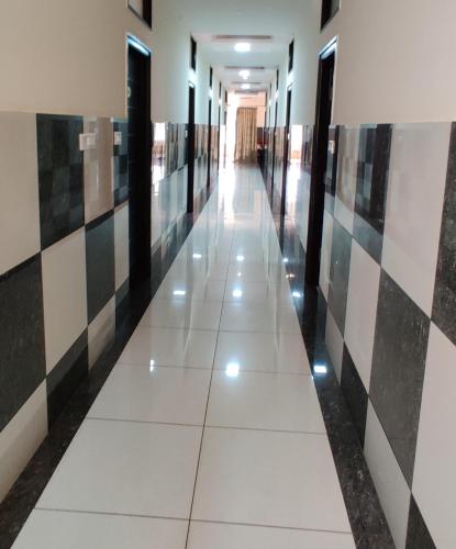 a hallway in a building with black and white tiles at Suvarna Suits in Mysore