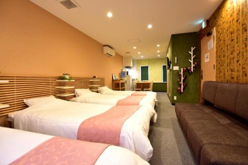 ein Hotelzimmer mit 4 Betten und einem Sofa in der Unterkunft サクラストーリー in Kyoto
