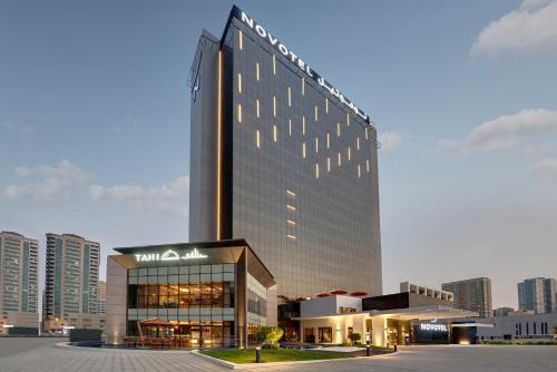 un grand bâtiment avec un panneau en haut dans l'établissement Novotel Sharjah Expo Centre, à Charjah