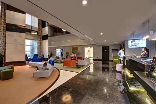 a lobby of a building with people sitting in chairs at Novotel Sharjah Expo Centre in Sharjah
