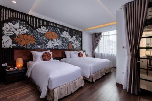 two beds in a hotel room with a floral wall at Hanoi Center Silk Lullaby Hotel and Travel in Hanoi