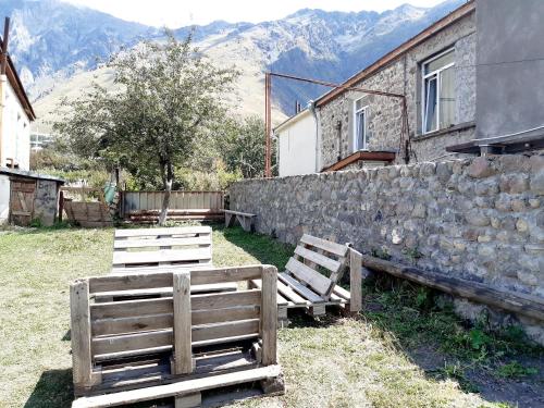 deux bancs en bois assis à côté d'un mur en pierre dans l'établissement Inside, à Kazbegi
