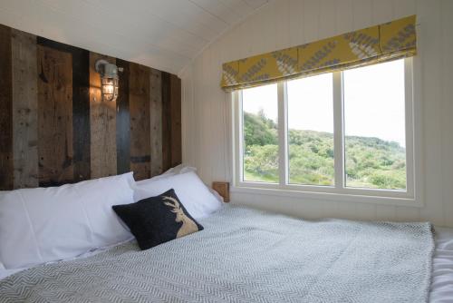 a bedroom with a white bed with a window at West Coast Hideaways in Nedd