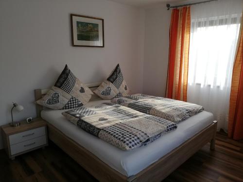 een slaapkamer met een bed met kussens en een raam bij Landhaus Maria in Tettenweis