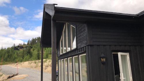 a black house with large windows on a road at Lillebjørn in Trysil