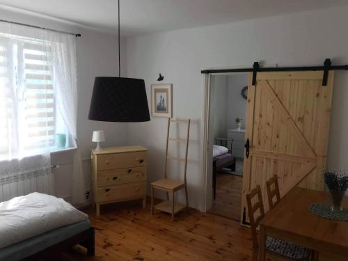 ein Schlafzimmer mit einer Tür, einem Tisch und einem Bett in der Unterkunft Domek przy Rajskiej in Jerzmanowice