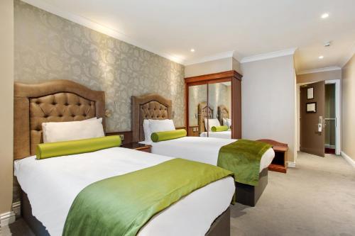 a hotel room with two beds with green and white sheets at Drury Court Hotel in Dublin