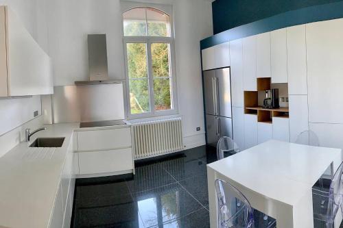 eine Küche mit weißen Schränken und einem großen Fenster in der Unterkunft Gîte de Lafleur in Dury