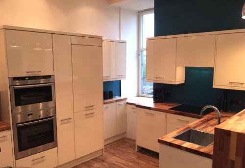 a kitchen with white cabinets and a sink at Pineapple Apartments in Aberdeen