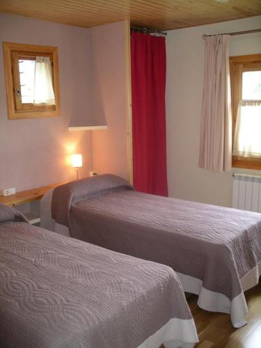 a hotel room with two beds and a red curtain at Hostal D'Éller in Éller