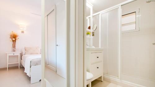 una camera da letto bianca con un letto e uno specchio di Apartamento Pine Beach en Alcudia a Alcudia